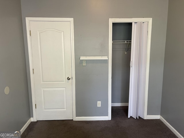 unfurnished bedroom with dark carpet and a closet