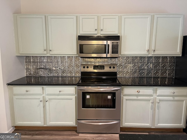 kitchen featuring white cabinetry, stainless steel appliances, dark hardwood / wood-style flooring, and backsplash