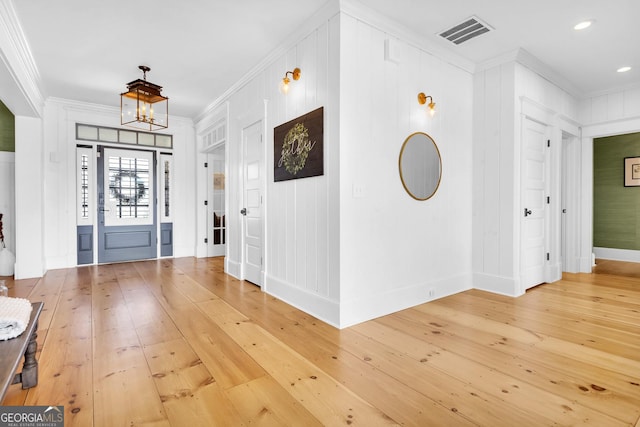 entryway with ornamental molding, hardwood / wood-style floors, and a chandelier