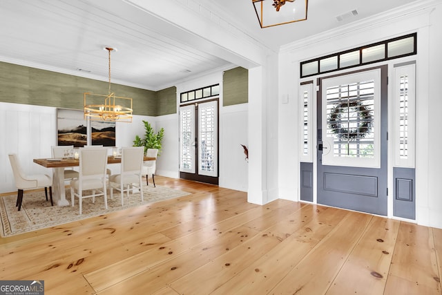 entryway featuring french doors, crown molding, a chandelier, and hardwood / wood-style flooring