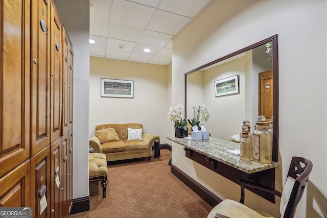 living area featuring carpet and a drop ceiling