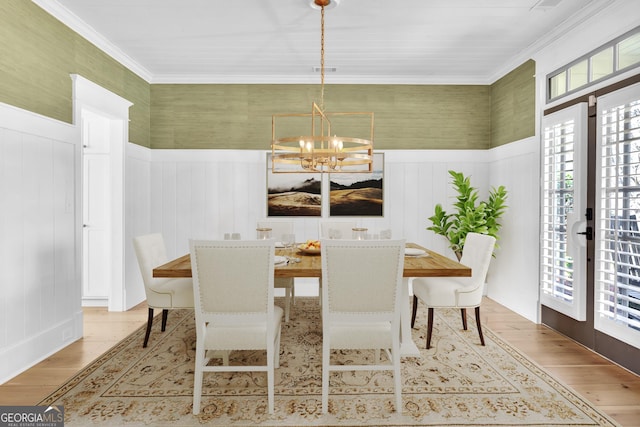 dining space with wood-type flooring, crown molding, and a chandelier