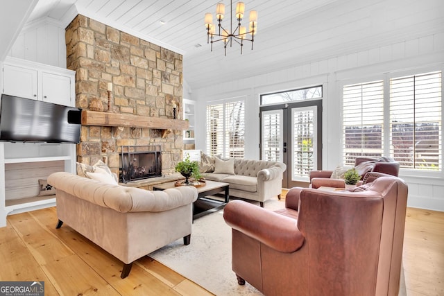 living room featuring lofted ceiling, a wealth of natural light, light hardwood / wood-style flooring, and a stone fireplace