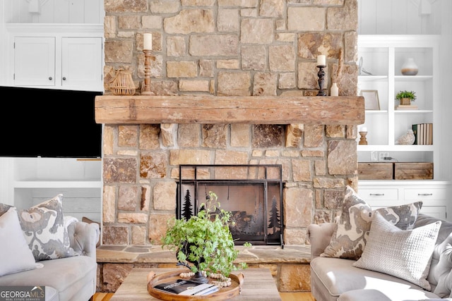 living room featuring built in shelves and a stone fireplace