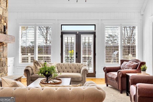 living room featuring crown molding, a wealth of natural light, french doors, and light wood-type flooring