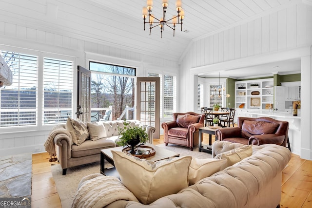 living room featuring lofted ceiling, a chandelier, and light hardwood / wood-style flooring