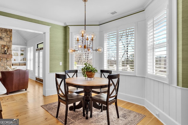 dining area with built in features, ornamental molding, light hardwood / wood-style floors, and a chandelier