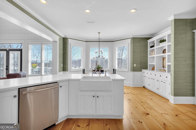 kitchen with sink, white cabinets, hanging light fixtures, ornamental molding, and stainless steel dishwasher