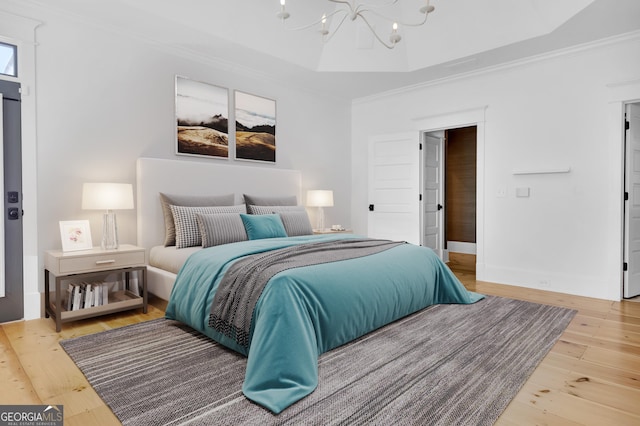 bedroom with crown molding, a notable chandelier, a tray ceiling, and hardwood / wood-style flooring