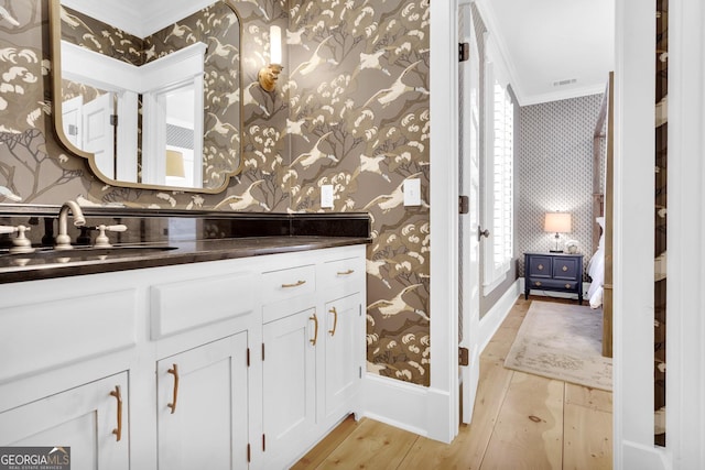 bathroom featuring hardwood / wood-style flooring, ornamental molding, and vanity