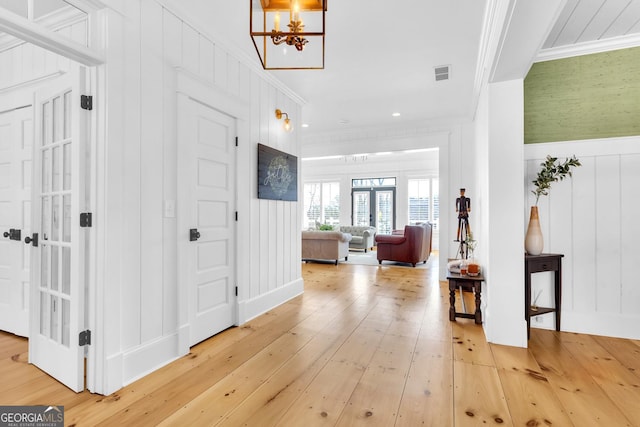 foyer featuring wood-type flooring, ornamental molding, and french doors