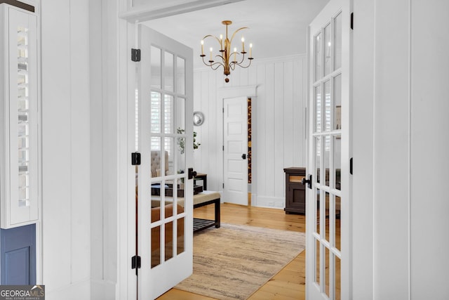 interior space featuring wood-type flooring, french doors, and a chandelier