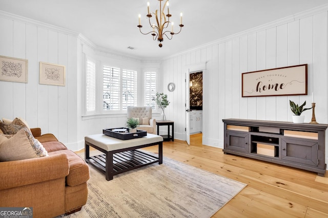 living room with hardwood / wood-style flooring, crown molding, and an inviting chandelier