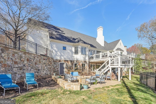 back of house featuring a wooden deck, an outdoor living space, a patio, and a lawn