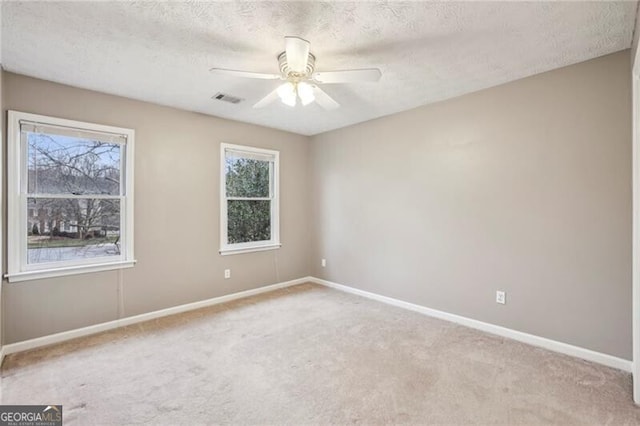 spare room featuring light carpet, ceiling fan, and a textured ceiling