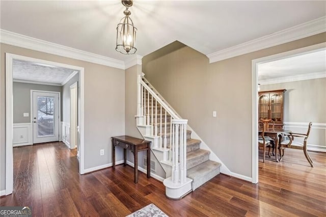 stairway with ornamental molding, hardwood / wood-style floors, and a chandelier