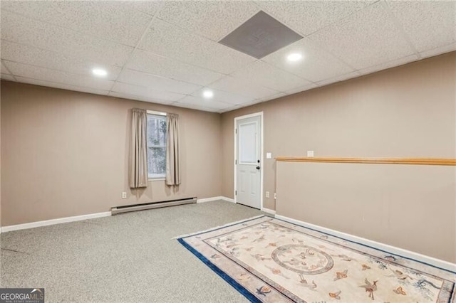 carpeted empty room with a baseboard heating unit and a drop ceiling