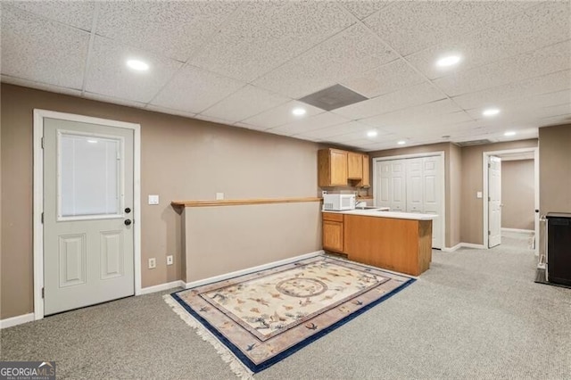 kitchen featuring a paneled ceiling, light colored carpet, and kitchen peninsula