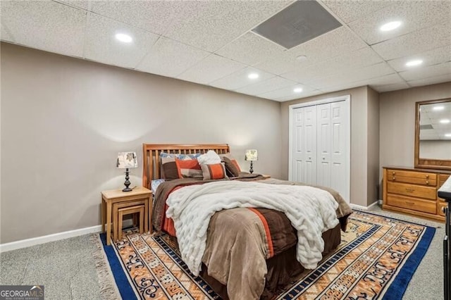 carpeted bedroom featuring a drop ceiling and a closet