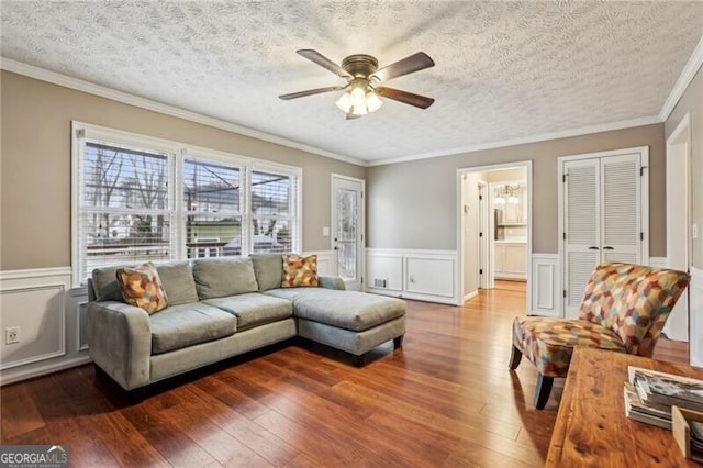 living room featuring hardwood / wood-style floors, ornamental molding, a textured ceiling, and ceiling fan