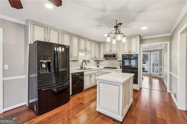 kitchen featuring sink, hardwood / wood-style floors, a center island, black appliances, and decorative light fixtures