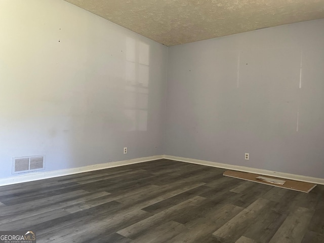 spare room with dark hardwood / wood-style floors and a textured ceiling