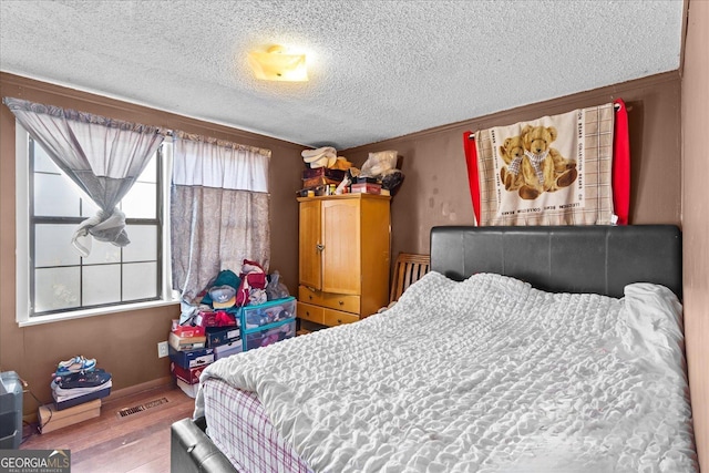 bedroom with light hardwood / wood-style flooring and a textured ceiling