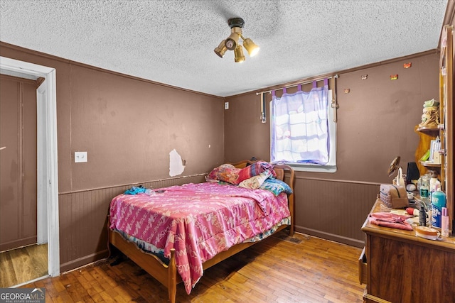 bedroom featuring hardwood / wood-style floors, ornamental molding, and a textured ceiling