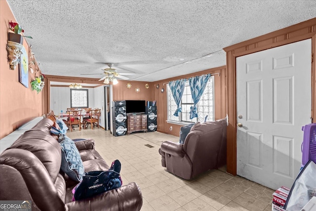 living room with ceiling fan, a textured ceiling, and wood walls