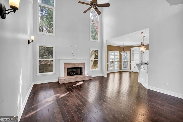 unfurnished living room with a high ceiling, dark hardwood / wood-style flooring, ceiling fan, and a fireplace