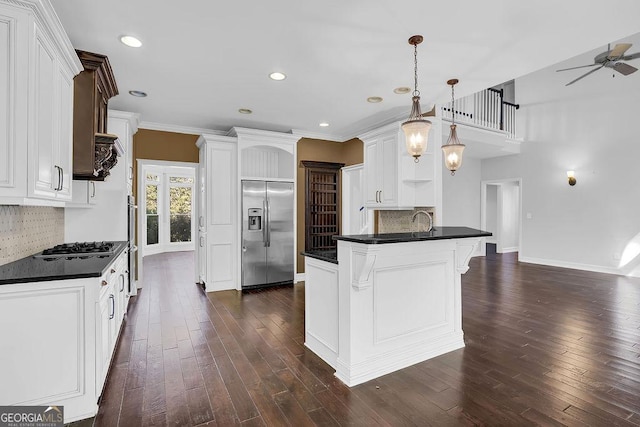 kitchen with decorative light fixtures, a center island, dark hardwood / wood-style flooring, stainless steel appliances, and white cabinets