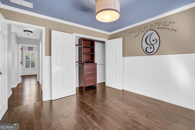 unfurnished bedroom featuring crown molding, dark wood-type flooring, and a closet