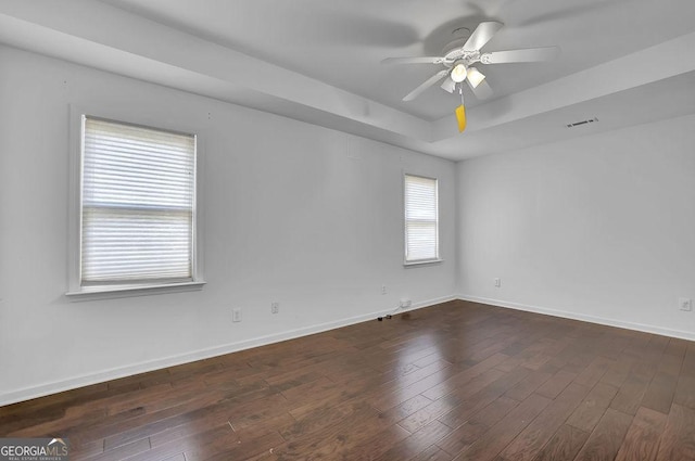 spare room featuring ceiling fan, a tray ceiling, and dark hardwood / wood-style floors