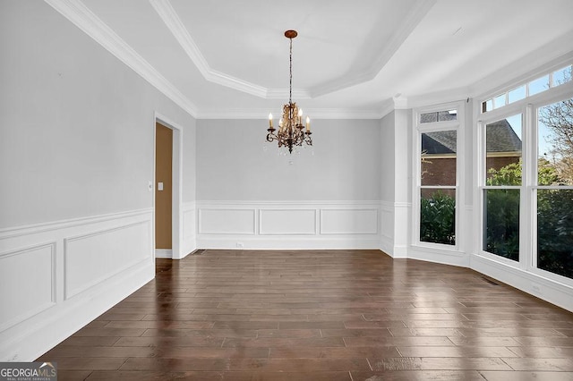 unfurnished dining area featuring crown molding, a notable chandelier, dark hardwood / wood-style flooring, and a tray ceiling