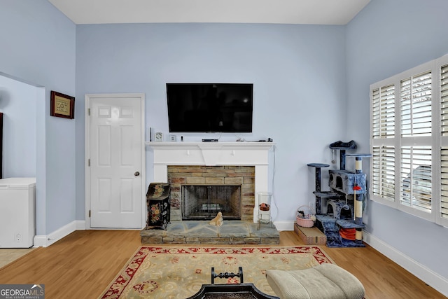 living room with a fireplace, wood finished floors, and baseboards