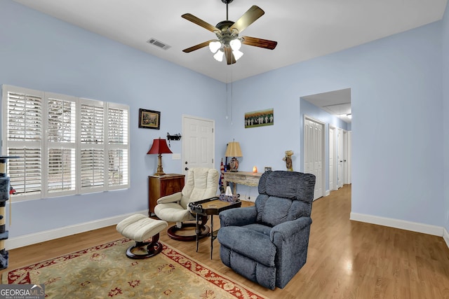 sitting room featuring visible vents, a ceiling fan, attic access, wood finished floors, and baseboards