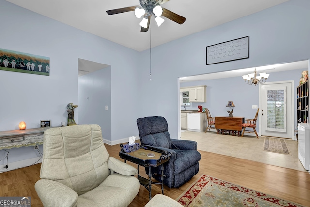 sitting room featuring ceiling fan with notable chandelier, wood finished floors, and baseboards