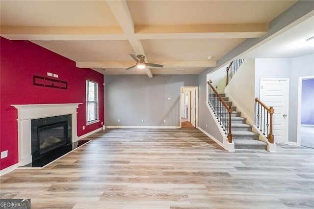 unfurnished living room with coffered ceiling, ceiling fan, beam ceiling, and light hardwood / wood-style flooring