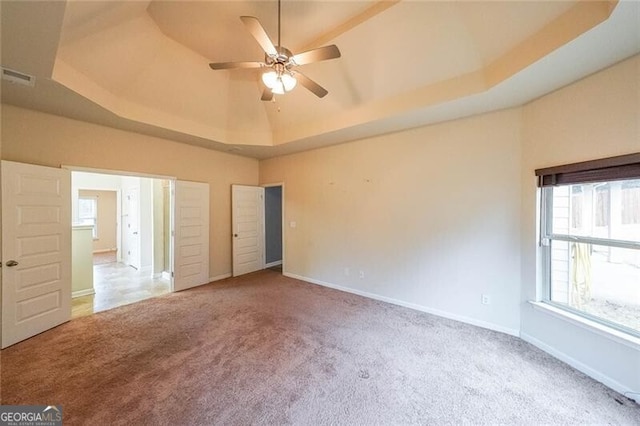 unfurnished bedroom featuring a tray ceiling and carpet floors