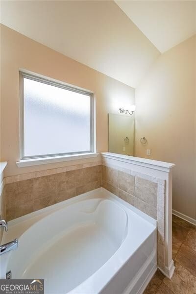 bathroom featuring lofted ceiling and a bathtub