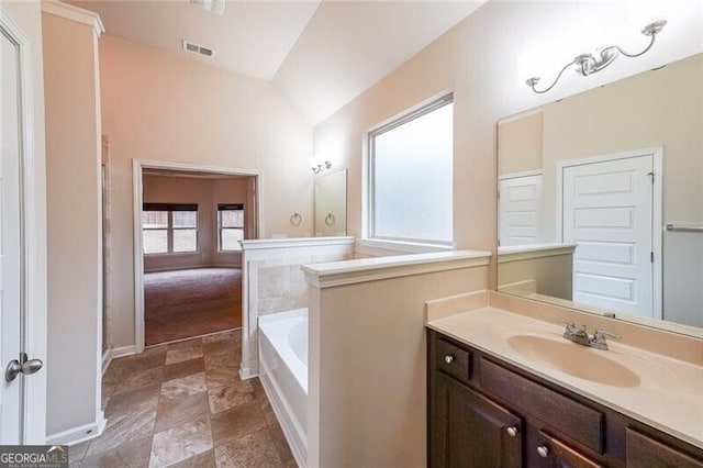 bathroom with vanity, vaulted ceiling, and a bath