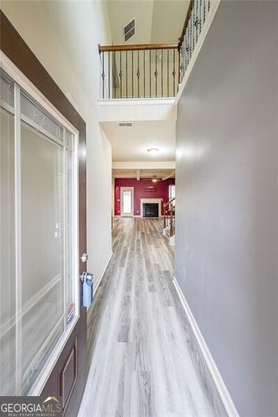 corridor featuring a towering ceiling and light hardwood / wood-style floors