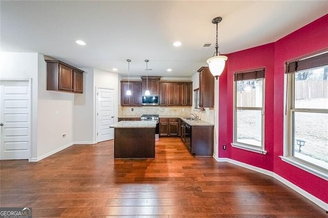 kitchen featuring stainless steel appliances, decorative light fixtures, dark hardwood / wood-style flooring, and a kitchen island