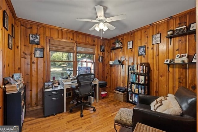 office featuring crown molding, light hardwood / wood-style flooring, ceiling fan, and wood walls