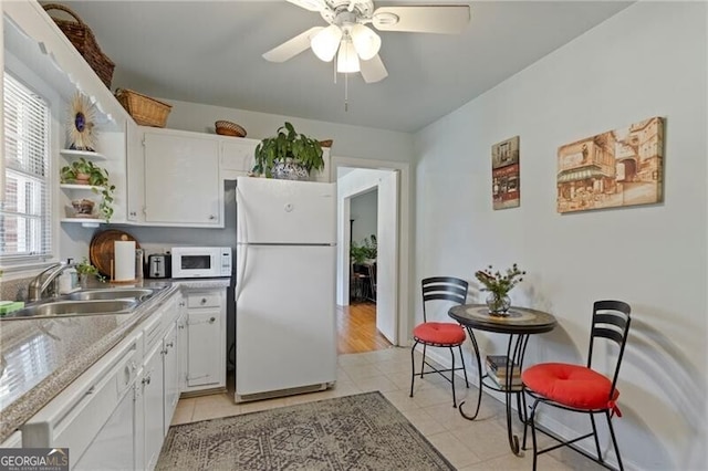 kitchen with light tile patterned flooring, white appliances, sink, and white cabinets