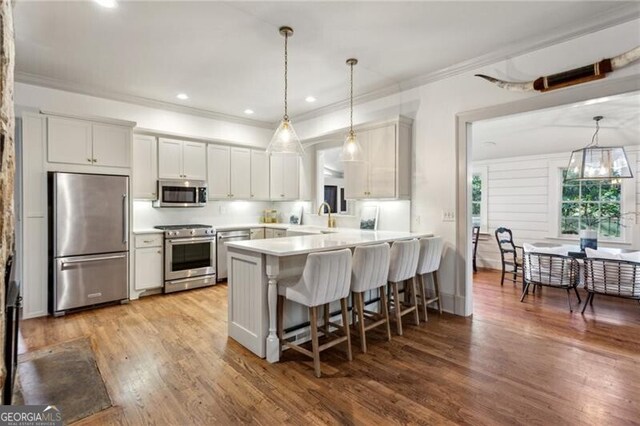 kitchen with a kitchen bar, white cabinetry, kitchen peninsula, pendant lighting, and stainless steel appliances