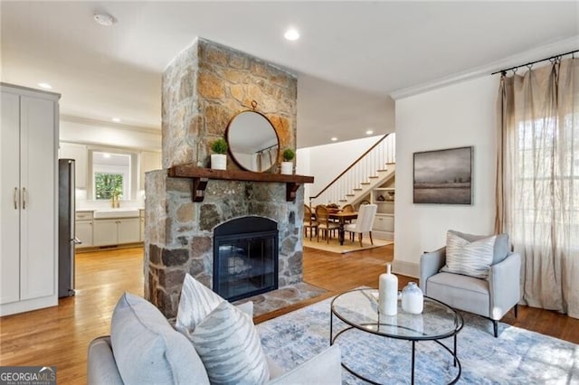 living room featuring light hardwood / wood-style flooring, sink, crown molding, and a fireplace