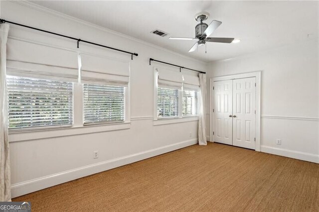 unfurnished bedroom featuring ceiling fan, ornamental molding, light carpet, and a closet