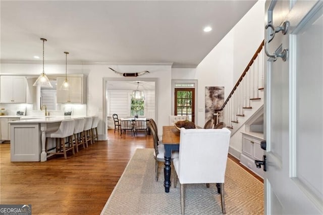 dining space with ornamental molding, sink, and hardwood / wood-style floors