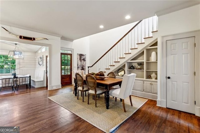 dining space with dark hardwood / wood-style floors, an inviting chandelier, and built in shelves